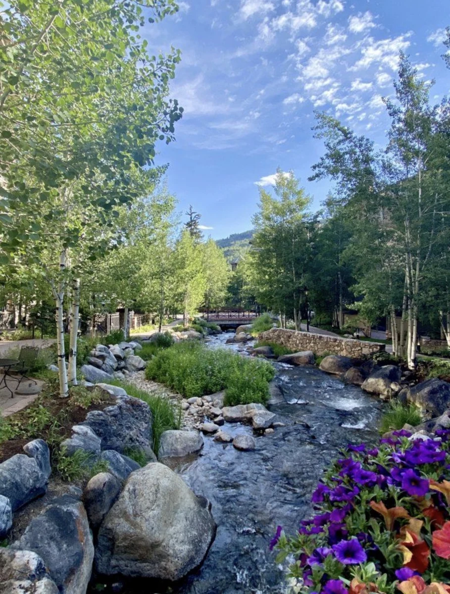Gore Creek flowing through Vail in summer with flowers, trees and mountains
