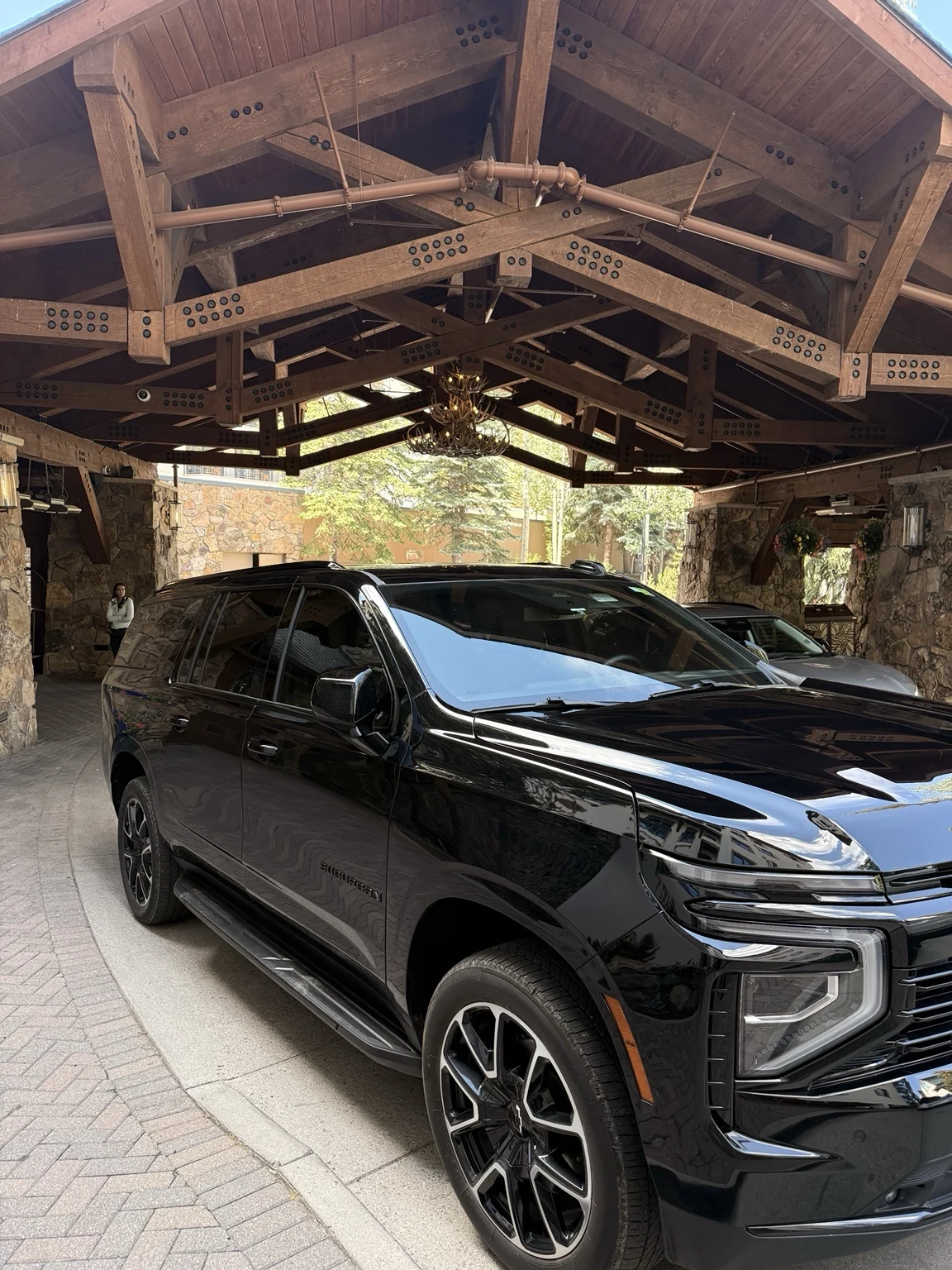 Elite Ride black Chevrolet Suburban at a timber and stone hotel entrance